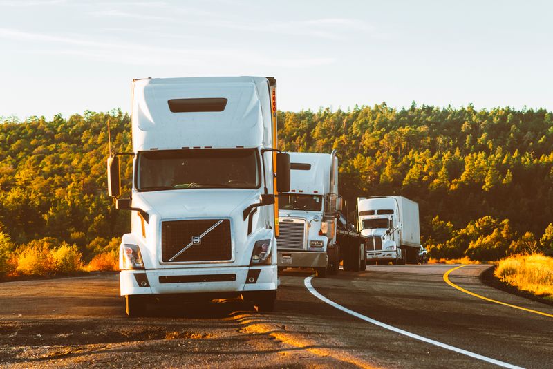 Large commercial semi-truck driving on a highway at sunset